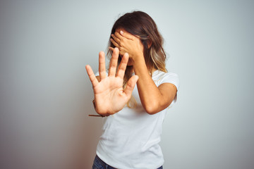 Poster - Young beautiful woman wearing casual white t-shirt over isolated background covering eyes with hands and doing stop gesture with sad and fear expression. Embarrassed and negative concept.