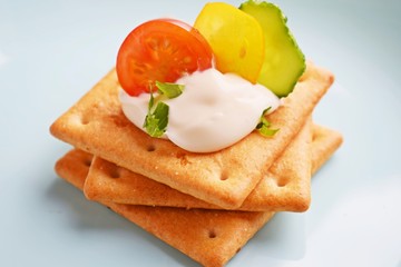 Wall Mural - Delicious crackers with cheese sauce and vegetables.Snack on wooden background.