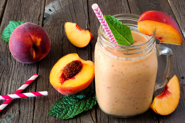 Wall Mural - healthy peach smoothie in a mason jar glass. close up table scene against a rustic wood background.