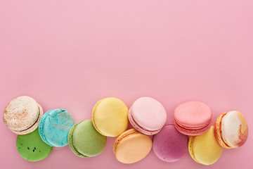 Wall Mural - top view of multicolored delicious French macaroons on pink background with copy space