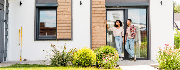 panoramic shot of african american man and woman standing outside near house