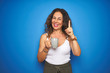 © Krakenimages.com - Middle age senior woman drinking a cup of coffee over blue isolated background surprised with an idea or question pointing finger with happy face, number one