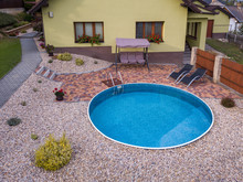 Small Home Swimming Pool With Two Black Sun Loungers And Rocking Bench