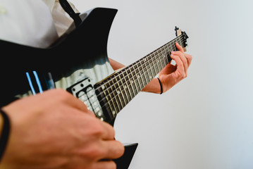 Close-up of the hands of a guitarist performing a song while pressing the strings.