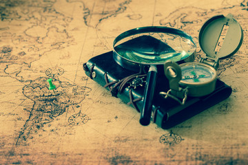 Fototapete - old map with compass, notebook and magnifying glass.  The concept of searching for interesting places or treasures around the world.
