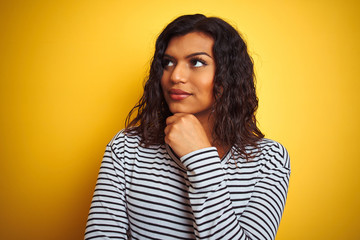 Wall Mural - Transsexual transgender woman wearing striped t-shirt over isolated yellow background serious face thinking about question, very confused idea