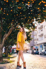 Wall Mural - girl on city street in dress and scarf. trees with oranges.