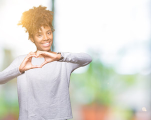 Beautiful young african american woman over isolated background smiling in love showing heart symbol and shape with hands. Romantic concept.