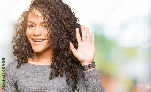 Young Beautiful Woman With Curly Hair Wearing Grey Sweater