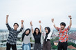 © Odua Images - five young people hanging out and raise hand together on the building rooftop