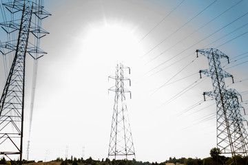 Three power line towers with halo from Sun and clouds