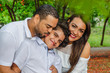 © Francisco - couple of Latin American men and women, with boy suffers autism, happy in a portrait family outdoors together in a park, the three laughing hugging