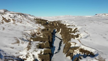Wall Mural - panoramic drone shot flying over snowy barren mountain landscape and narrow canyon, beautiful natura