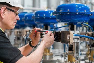 a service engineer checks an pneumatic valve with a screwdriver