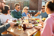 © Syda Productions - leisure and people concept - happy friends eating and drinking at barbecue party on rooftop