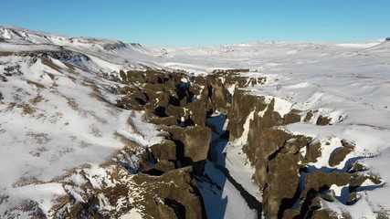 Wall Mural - retreating drone shot flying over snowy barren mountain landscape and narrow canyon, beautiful plain