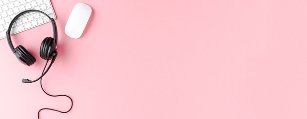 call center desktop with headset and accessories on pink table. panoramic banner. top view