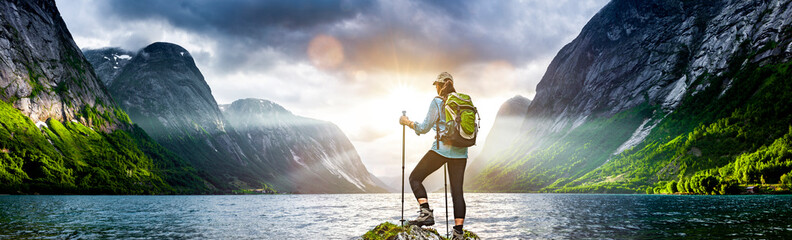 frau mit rucksack beim wandern an einem fjord in norwegen