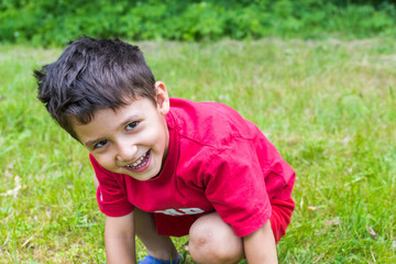 Poster - cheerful boy sitting on the grass in the summer