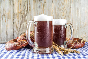 Wall Mural - Oktoberfest festive background with traditional Bavarian checkered tablecloth, pretzels and beer mugs.