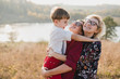 © anna_gorbenko - Samesex caucasian lesbian family with a child and a dog walking outdoors on the background of beautiful nature. Mothers having fun with their son.