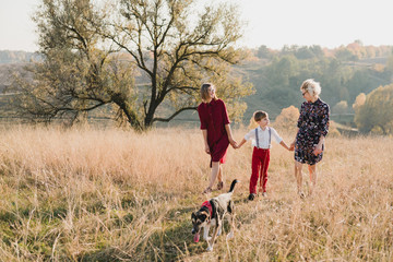 Two women with boy and dog walking in field