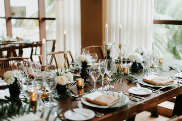 Wall Mural - modern and bohemian table decorations at wedding reception, table setting with candle sticks, palm leafs, and flowers