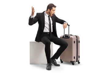 Sticker - Businessman in panic sitting with a suitcase and looking at his watch