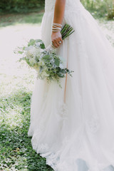 Wall Mural - Bride holding wedding flower bouquet, white lace gown, close up