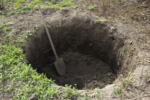 Fotografía Deep pit in the ground. In the pit lies a shovel. Digging a hole.