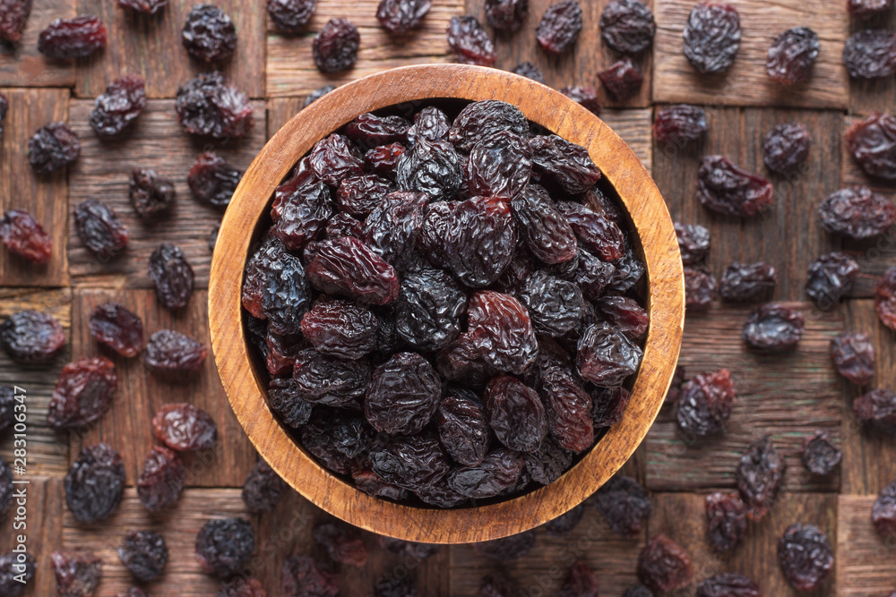 dried grapes, dark raisins in wooden bowl, top view. - obrazy, fototapety, plakaty 