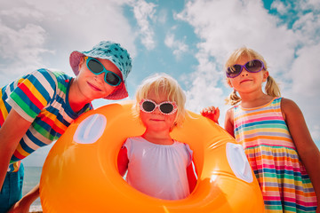 Wall Mural - happy cute boy and girls play with floaties on beach