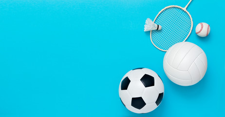 Wall Mural - Assorted sports equipment including a basketball, soccer ball, volleyball, baseball, badminton racket on a light blue background