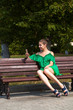© Andrey_Arkusha - Sexy beautiful caucasian girl in green dress sitting on a bench with a phone in hand