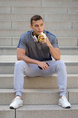 Wall Mural - Young latin man eating banana fruit runner fitness portrait format sports training