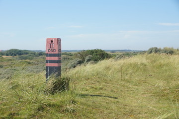 Wall Mural - A beacon in the dunes with a lighthouse on the horizon on Ameland