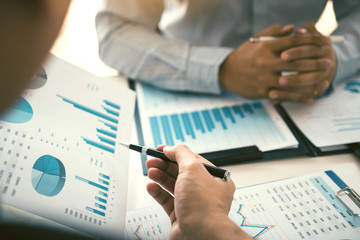 Wall Mural - Two business partnership coworkers analysis strategy and gesturing with discussing a financial planning graph and company budget during a budget meeting in office room.