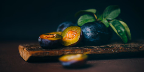 Wall Mural - Red cherry plum with green leaves on dark background. Toned image with copy space.