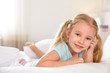 © New Africa - Portrait of cute little girl resting on large bed