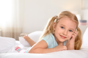 Sticker - Portrait of cute little girl resting on large bed