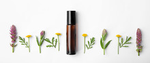 Bottle Of Essential Oil And Wildflowers On White Background, Top View