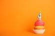 © New Africa - Birthday cupcake with number four candle on orange background, space for text