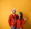 © New Africa - Young couple in Christmas sweaters and hats on yellow background. Space for text