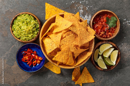 Fotografía top view of Mexican nachos served with guacamole, limes, chili peppers and salsa