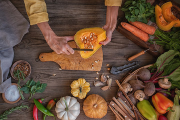 Wall Mural - Chef cook preparing vegetables in her kitchen. Healthy food clean eating selection: vegetables, seeds, spice on dark background.