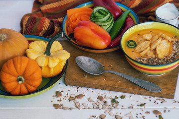 Wall Mural - Vegetable soup with seeds and croutons over wooden background. Healthy vegetarian food. Cooking preparation. Pumpkin, red paprika, carrot on rustic background for Thanksgiving Day recipes, menu card.