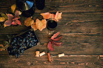 Wall Mural - Red wine with bottle, glass and grapes on wooden background. Wine header image. Wineglass. Display in a winery or tavern of red grapes in a wooden box. Concept of the grape harvest, wine making.