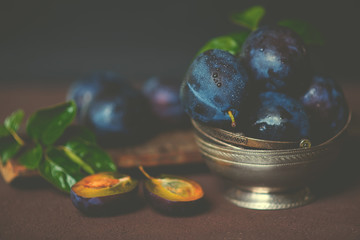 Wall Mural - Bowl with ripe juicy plums on table. Fresh organic plums. Summer harvest. Autumn harvest. Beautiful still life. Toned image. Selective focus.