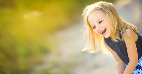 lovely cute little girl playing outdoors at sunset, walking on the field and having fun, happy childhood