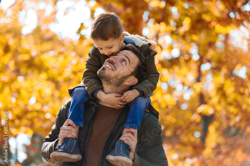 Fotografía Happy father and little son playing and having fun outdoors over autumn park bac